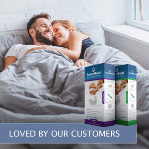 Couple cuddling in bed, after a restful nights sleep, thanks to SnoreMeds. Photo includes picture of SnoreMeds Men's & Women's packs, with wording - "Loved by our customers"!